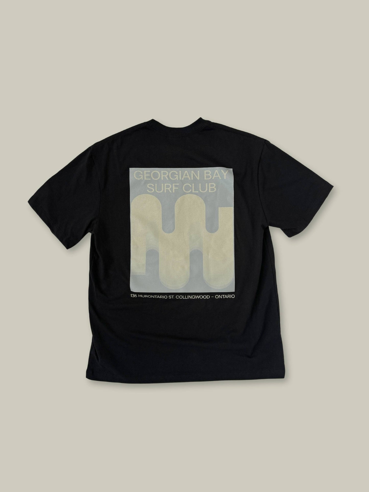 Full view of the back oversized Wave Icon Shadow graphic in beige and tan, on the Black Boomer tee shirt