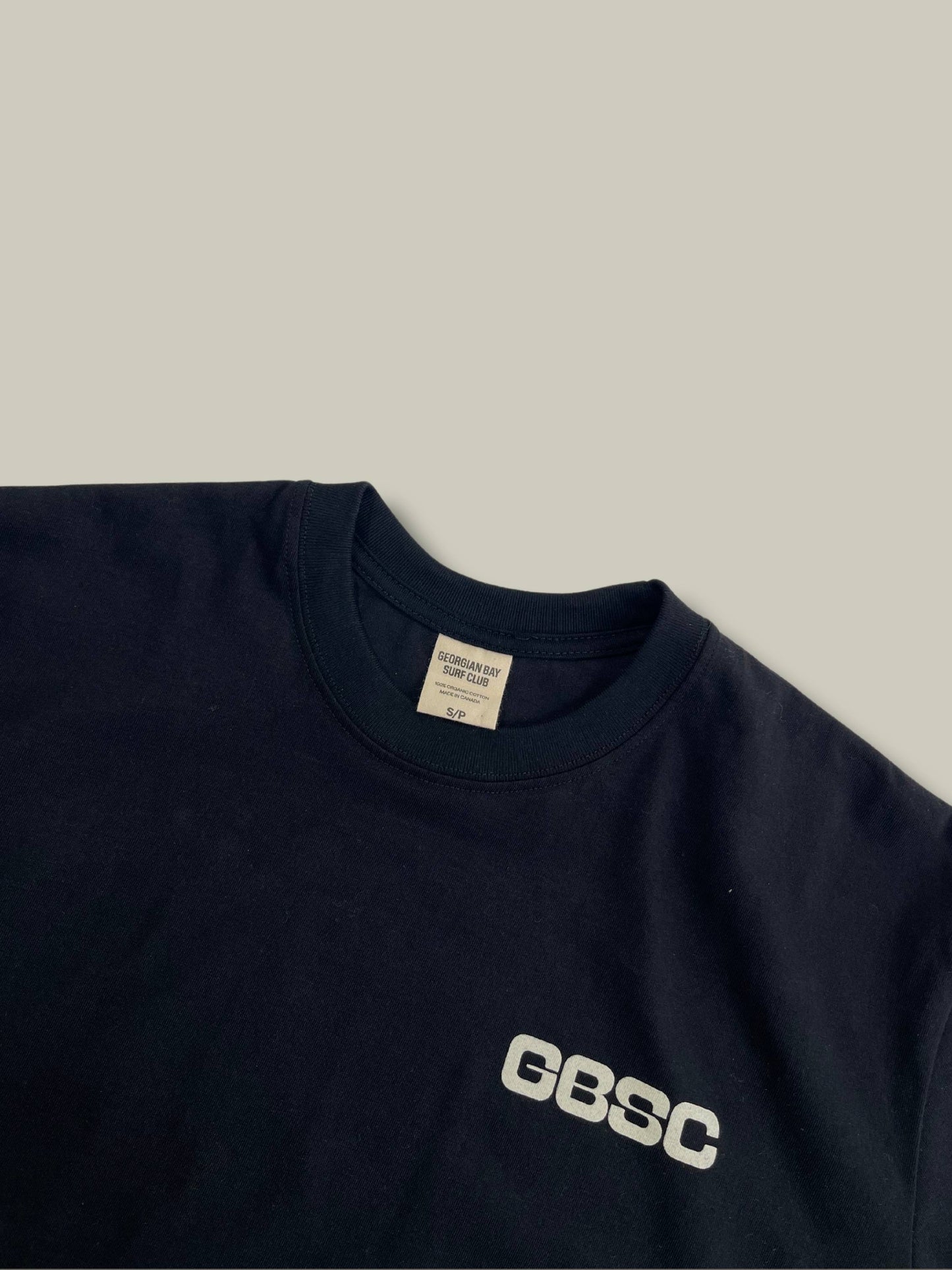Detailed view of the beige GBSC graphic on front chest of the Black Boomer tee shirt