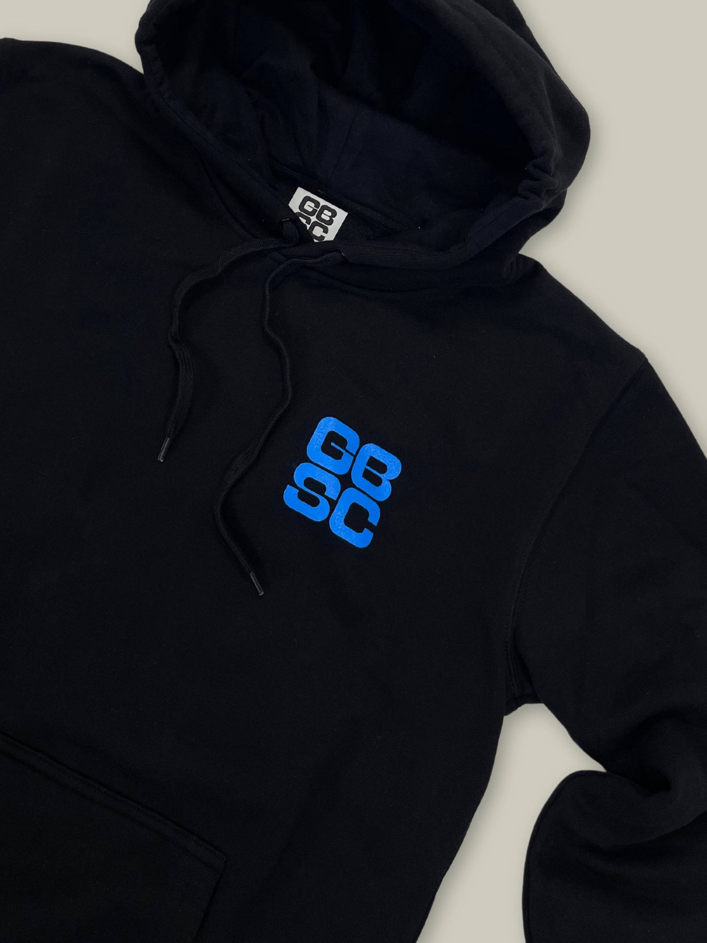 Detailed view of cobalt blue stacked GBSC graphic on chest of GBSC Daily Driver Hoodie sleeve